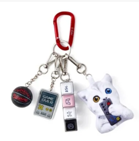 Keychain with multiple charms including a white cat-shaped charm, Game Boy, and other small items on a white background.